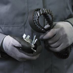 A Quick Lane technician holding two belt hoses.